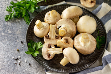 Champignons. Fresh white mushrooms in bowl on stone background. Free space for your text.