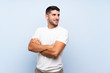 © luismolinero - Caucasian handsome man over isolated blue background with arms crossed and happy