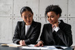 © VideoFlow - Smiling African American businesswoman and her Asian colleague discussing contract at office table. Concept of international communication and partnership