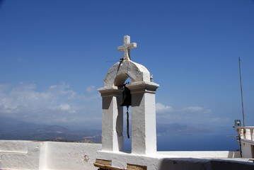 christian cross and bell against blue sky