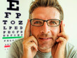 © TheVisualsYouNeed - Attractive man checking vision trying glasses at optometrist . guy on his 40s during optical examination testing spectacles for correcting myopia in eyes health care