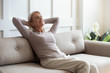 © fizkes - Older 50s female resting seated on couch with closed eyes