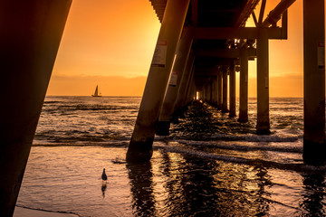 Jetty at The Spit, Queensland at sunrise with sailboat and seagull