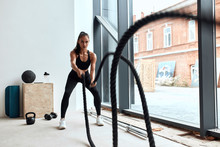 Sportive Caucasian Woman Training With Ropes In Gym, Cross Fit. Window Background