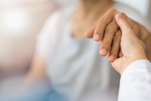 Geriatric Doctor Or Geriatrician Concept. Doctor Physician Hand On Happy Elderly Senior Patient To Comfort In Hospital Examination Room Or Hospice Nursing Home Or Wellbeing County.