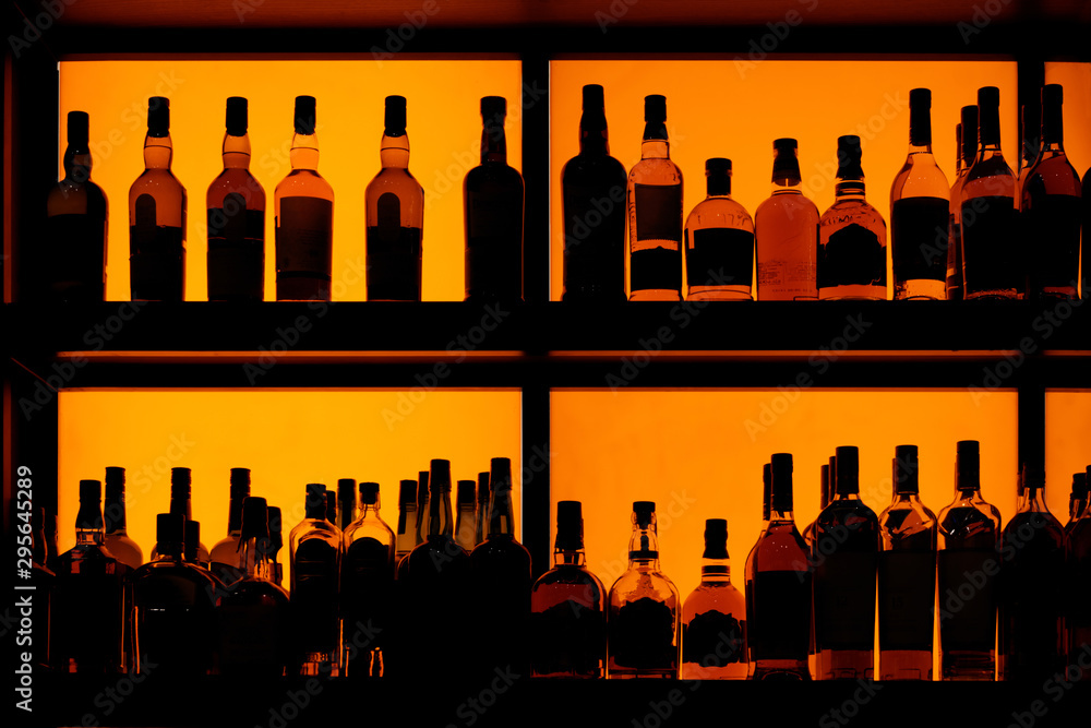 Bottles sitting on shelf in a bar - obrazy, fototapety, plakaty 