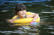 Happy girl with yellow floaty swimming in the lake