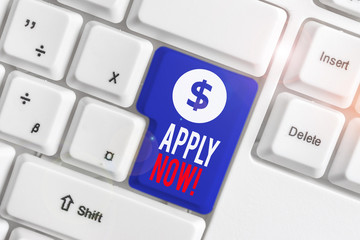 Text sign showing Apply Now. Business photo text request something officially in writing or by sending in form White pc keyboard with empty note paper above white background key copy space