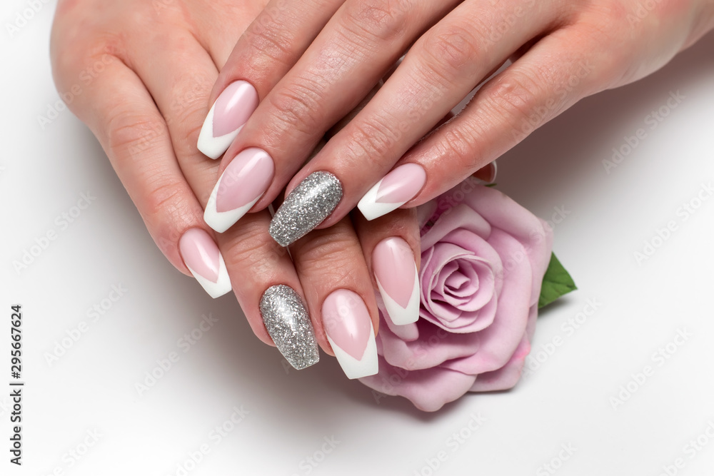 Wedding sharp French manicure with silver sequins on the ring fingers on a white background close-up on long nails with a pink rose in hand - obrazy, fototapety, plakaty 