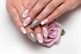 Wedding sharp French manicure with silver sequins on the ring fingers on a white background close-up on long nails with a pink rose in hand