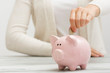 © Roman Motizov - woman hand putting money coin into piggy for saving money wealth and financial concept.