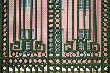 Green wrought iron geometric pattern on the gate against the pink building in Kuskovo Russia