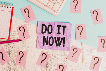 Text sign showing Do It Now. Business photo showcasing not hesitate and start working or doing stuff right away Writing tools, computer stuff and math book sheet on top of wooden table