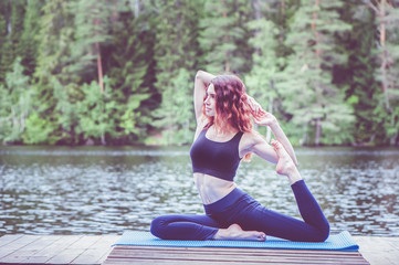 Wall Mural - Beautiful girl in a yoga pose on the lake. Eka Pada Rajakapotasana . One Legged King Pigeon Pose . The concept of peace, healthy lifestyle