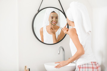 Wall Mural - Beautiful young woman applying facial mask at home