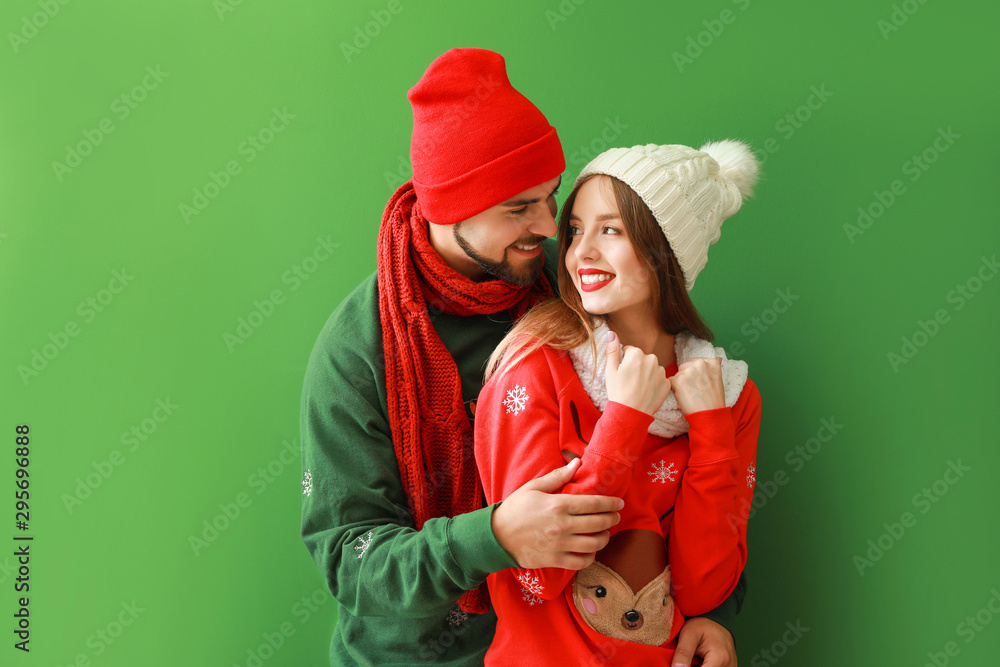 Happy young couple in Christmas clothes on color background