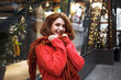 © Вероника Зеленина - Young beautiful woman walking at city street at cool christmas day in garland bacground. Wearing warm oversize sweater and scarf.