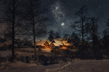 Beautiful Night Winter Christmas Landscape. View Of Snowy Village Houses Lit By Warm Light From The Window. Starry Night And A Hunch Of Christmas.