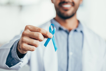 Prostate Cancer Awareness. Doctor man holding light Blue Ribbon for supporting people living and illness. Men Healthcare and World cancer day concept
