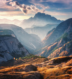 Fototapeta Fototapety góry  - Mountain canyon lighted by bright sunbeams at sunset in autumn in Dolomites, Italy. Landscape with mountain ridges, rocks, colorful trees and orange grass, alpine meadows, gold sunlight in fall. Alps