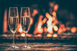 Two glasses of sparkling champagne in front of warm fireplace. Cozy relaxed magical atmosphere in a chalet house by the fireside. Snug holiday concept. Beautiful background with shimmering wine.