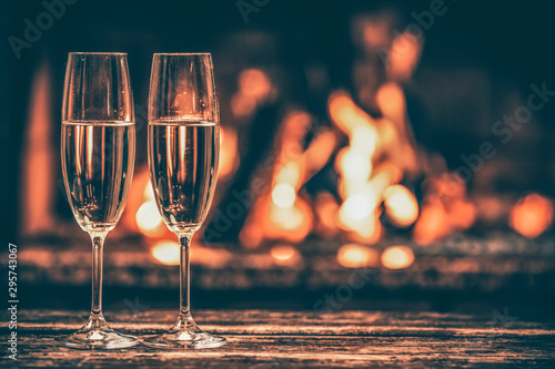 Two Glasses Of Sparkling Champagne In Front Of Warm Fireplace