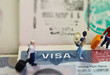 Miniature toys studio set up - expatriate business man and other travellers travel with visa on passport as background.
