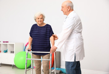 Poster - Doctor helping elderly woman with walking frame indoors