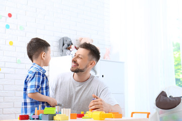 Wall Mural - Father and son playing at wooden table in light room