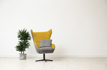 Stylish Living Room Interior With Comfortable Armchair And Houseplant Near White Wall. Space For Text