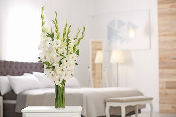 Wall Mural - Vase with beautiful white gladiolus flowers on wooden table in bedroom. Space for text