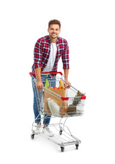 Wall Mural - Young man with full shopping cart on white background