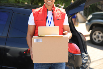 Sticker - Young courier holding parcels near delivery car outdoors