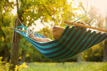 young man resting in comfortable hammock at green garden