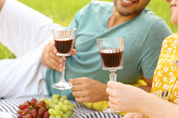 Poster - Young couple with glasses of wine having picnic outdoors, closeup