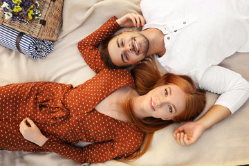 Wall Mural - Happy young couple lying on picnic blanket, top view