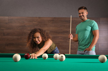 Wall Mural - Young man and woman playing billiard indoors