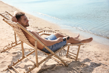 Wall Mural - Young man relaxing in deck chair on sandy beach