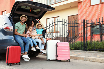 Wall Mural - Happy family with suitcases near car in city street