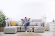 © New Africa - Young man relaxing on sofa under air conditioner at home