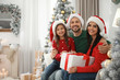 © New Africa - Portrait of happy family with Christmas gift at home, space for text