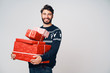 © baranq - Young man holding stack of Christmas presents, smiling at camera, isolated.