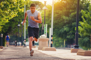Wall Mural - Man running sprinting on road. Fit male fitness runner during outdoor workout with sunset background