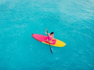 Wall Mural - Attractive woman on stand up paddle board on a quiet blue ocean. Sup surfing in sea