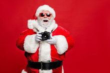 Portrait Of Excited Enthusiastic Santa Claus In Eyewear Eyeglasses Have Voyage Take Photo Wear Stylish Costume Cap Hat Belt Isolated Over Red Background
