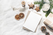 © tabitazn - Christmas blank greeting card mock-up scene. Festive winter wedding composition. Craft envelope, pine cone, gift box, orange fruit slices and fir tree branch on white table, linen background. Flat lay