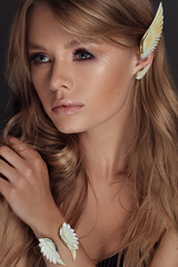 beautiful woman with perfect make up and hairstyle posing in studio in white jewellry set like angel wings