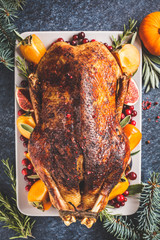 Wall Mural - Christmas baked duck with herbs and fruits on gray plate, blue background, top view.