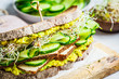 Big veggie sandwich with tofu, vegetables, sprouts and guacamole. Healthy vegan food concept.