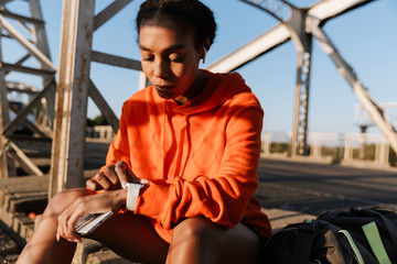 Wall Mural - Photo of african american woman using smartwatch and holding cellphone